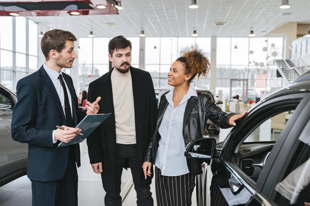 A couple talks with a car dealer