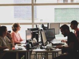 People work on computers at a shared workspace